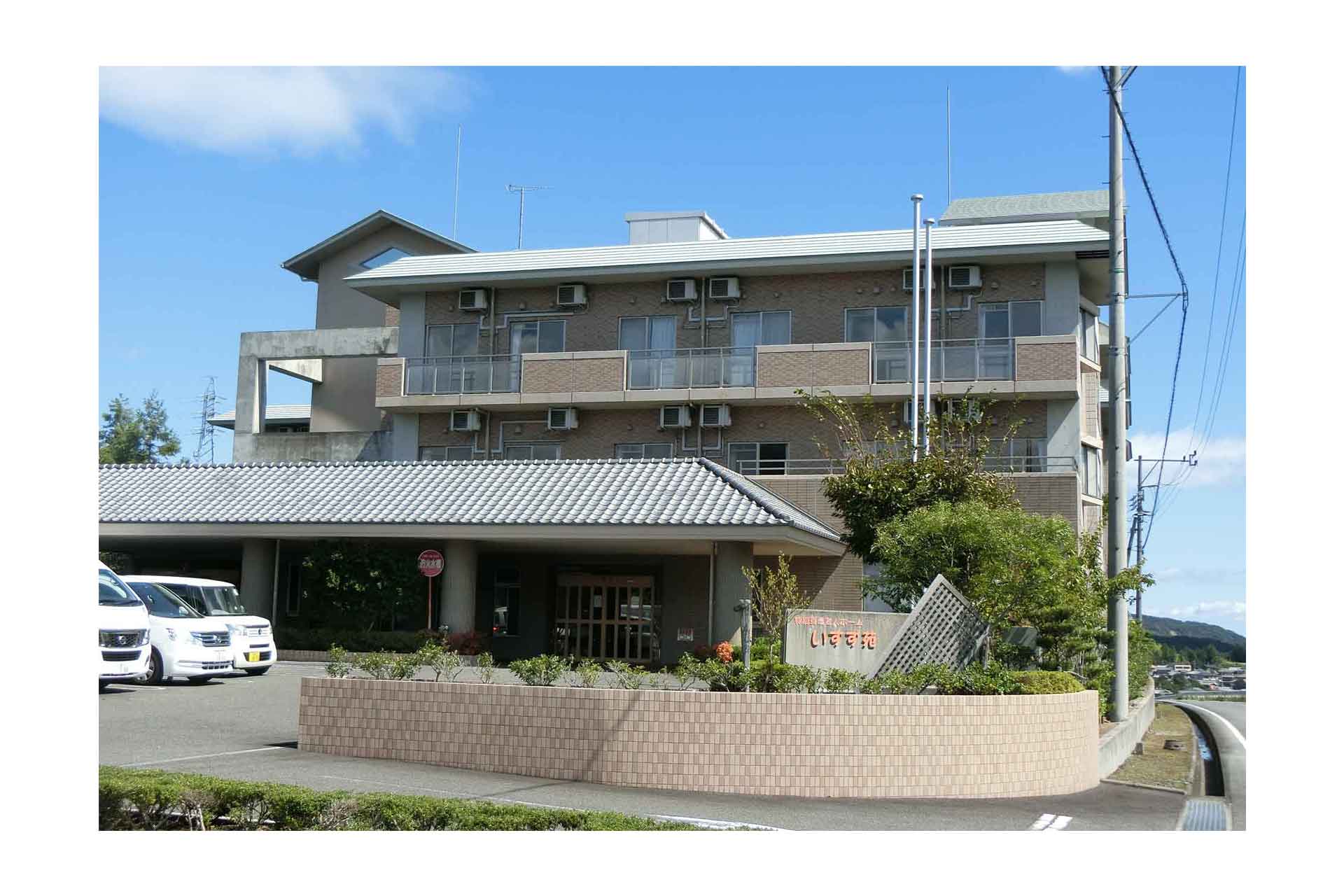 介護施設の建物外観。3階建てレンガ造りで駐車場と玄関が見える。